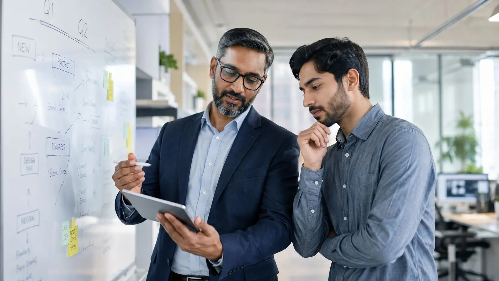 Due professionisti in ufficio discutono davanti a una lavagna bianca durante una sessione di brainstorming collaborativo.